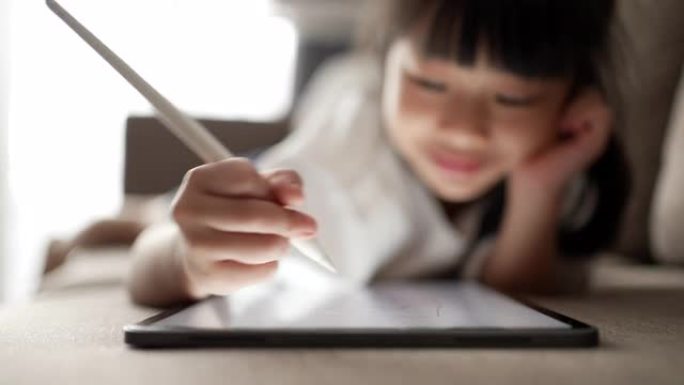 小女孩在数字平板电脑上写字在家进行电子学习的特写手