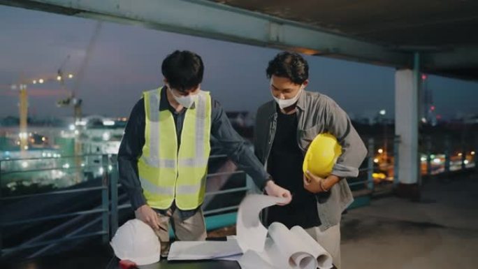 两名亚洲建筑商在现场咨询建设项目计划。