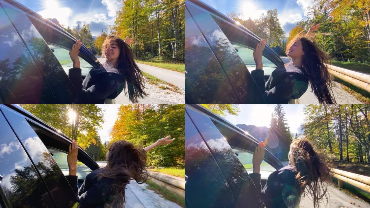 女人在温暖的秋日俯身从车窗外享受新鲜空气