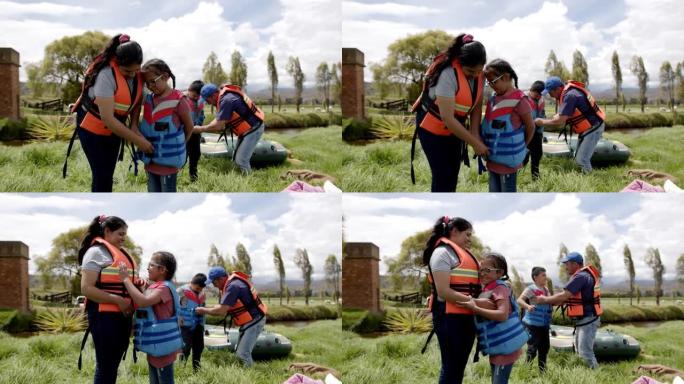 开朗的拉丁美洲家庭准备乘漂流船来保护孩子的安全背心