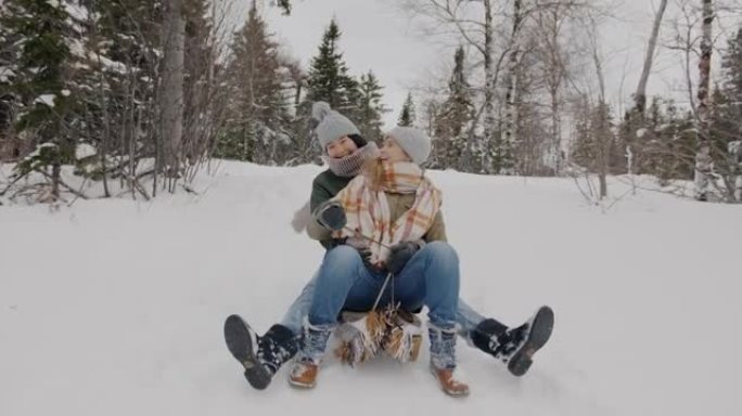 多莉拍摄了快乐的年轻女性朋友在冬天的树林中滑下雪橇的镜头