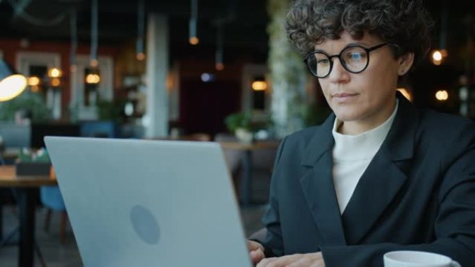 严肃的女人用笔记本电脑看着咖啡馆里的屏幕打字的慢动作