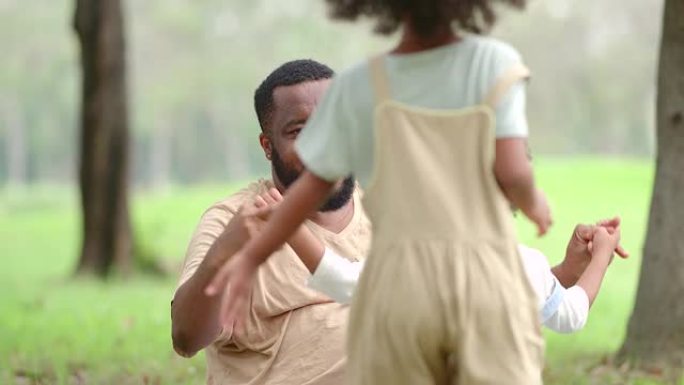 一对父子，一个黑人女儿，在公园玩耍。所有人在一起度过幸福的时候，每个人的脸上都在微笑。