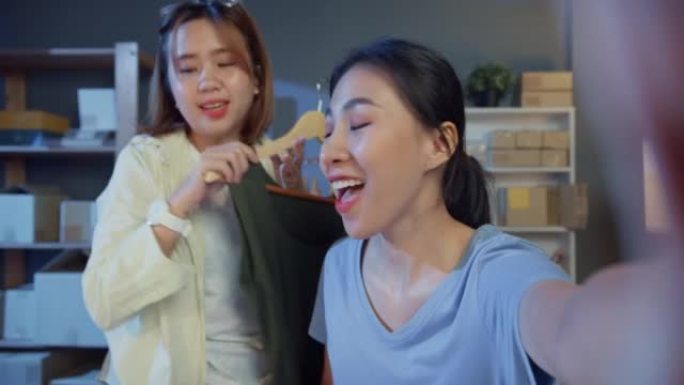 两名年轻的亚洲女孩时装设计师自拍看相机在线直播展示新系列产品晚上在商店收到顾客的订单。小企业，在线市