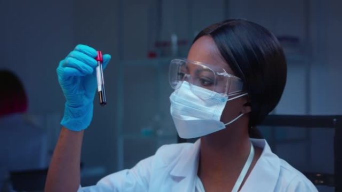 一位年轻的非洲裔女性实验室医生的特写镜头，看着带有血液样本的试管