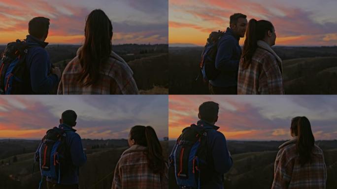日落时无忧无虑的情侣在山地风景上徒步旅行
