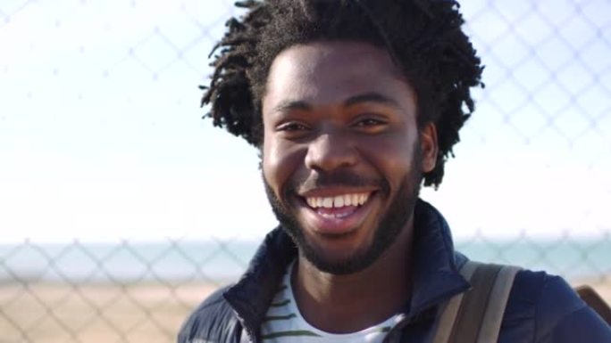 一个年轻黑人在镇上通勤时笑着笑的特写肖像。一个开朗的非洲裔美国男性的脸看起来很快乐，喜欢开玩笑。一个