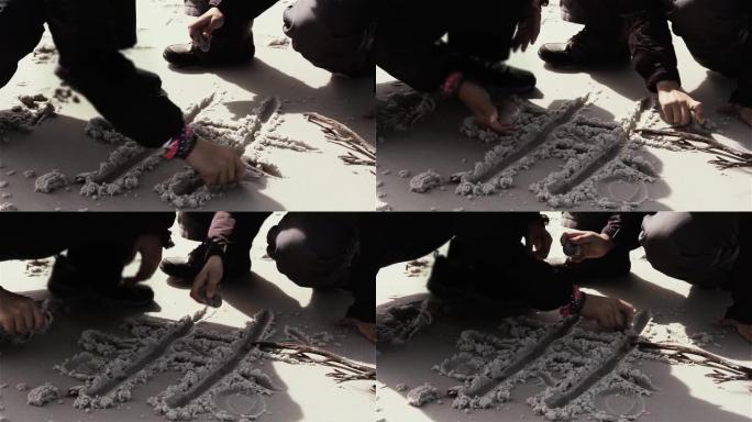 年轻女孩在白沙上玩井字游戏。特写。