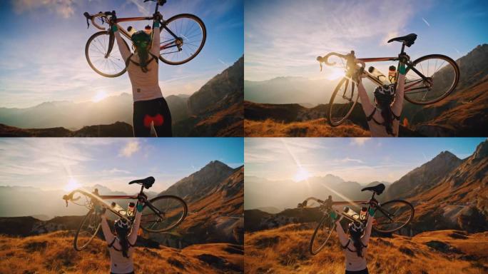 女骑自行车者在日出时在阳光明媚的山脉中抬起自行车