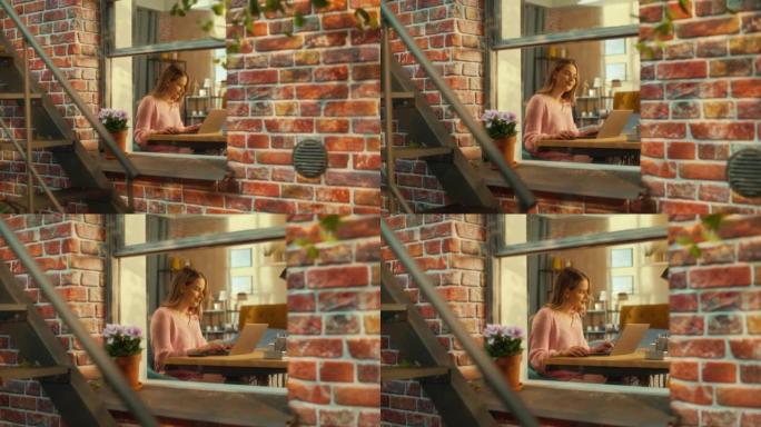 美丽的高加索女孩坐在布鲁克林风格的褐砂石房子的桌子后面，使用笔记本电脑。年轻女性浏览互联网，查看社交