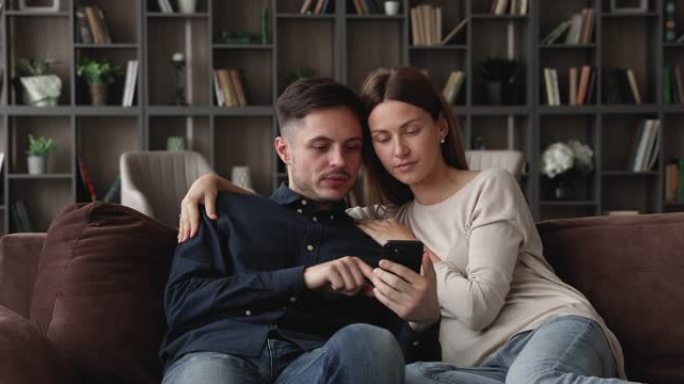 幸福的爱的年轻家庭夫妇使用智能手机。