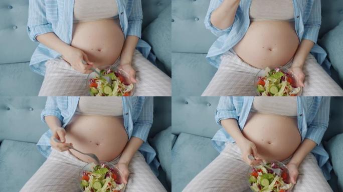 孕妇腹部和手拿着碗沙拉和在家吃饭的中间镜头