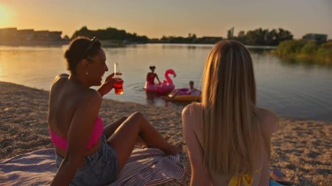 SLO MO两个年轻女人在海滩上度过美好时光时喝酒敬酒