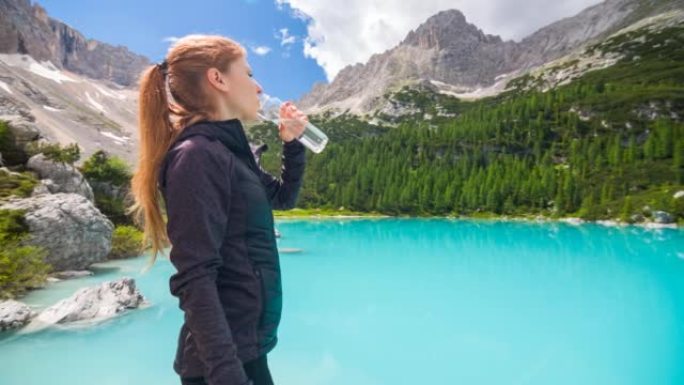 女人由绿松石山湖用可重复使用的水瓶补水