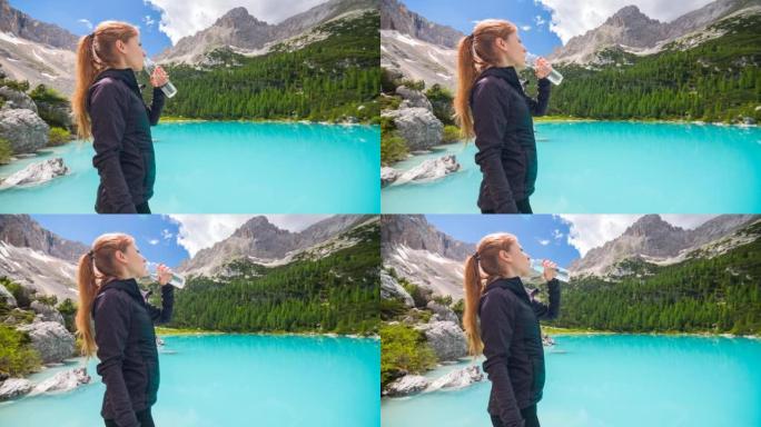 女人由绿松石山湖用可重复使用的水瓶补水