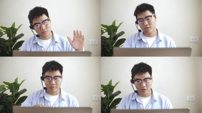 穿着蓝色休闲衬衫的亚洲男子在家里的笔记本电脑上进行视频会议，在家工作和远程工作