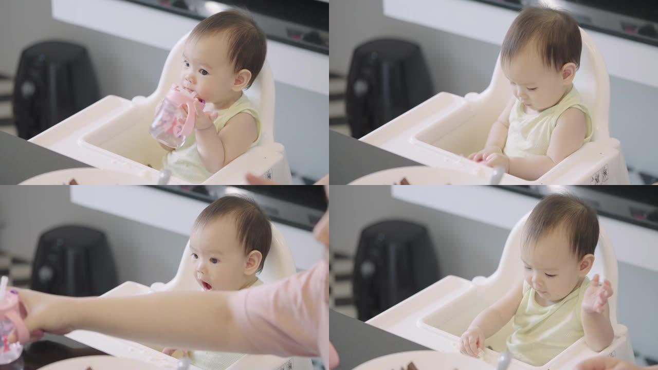 亚洲婴儿在婴儿椅上喝奶瓶牛奶