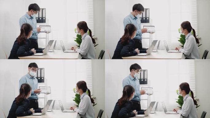 办公室正常工作的新概念，在办公室的会议上，戴着防护口罩的商人在数字平板电脑上展示