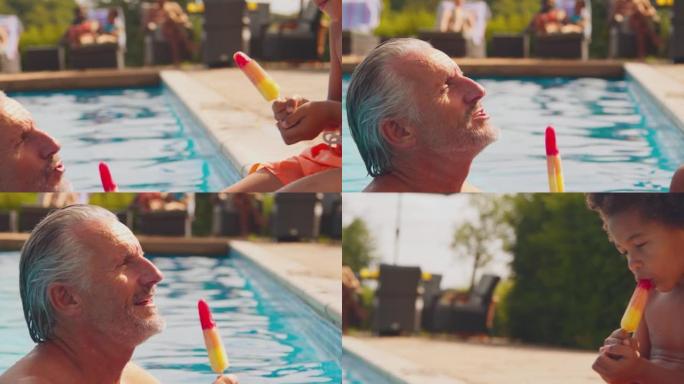 祖父和孙子在家庭暑假在游泳池边缘吃冰棍