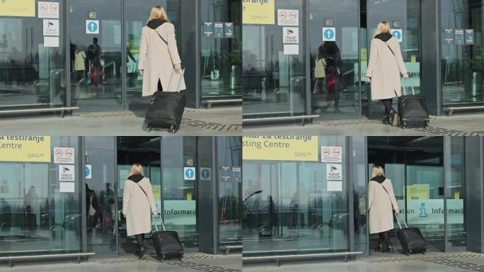 带着行李进入机场滑动玻璃门的女人