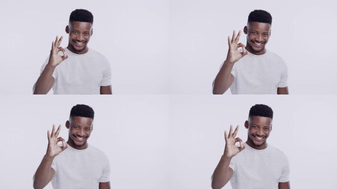 4k录像片段，一个年轻人站在摄影棚里的白色背景下，做出一个不错的手势