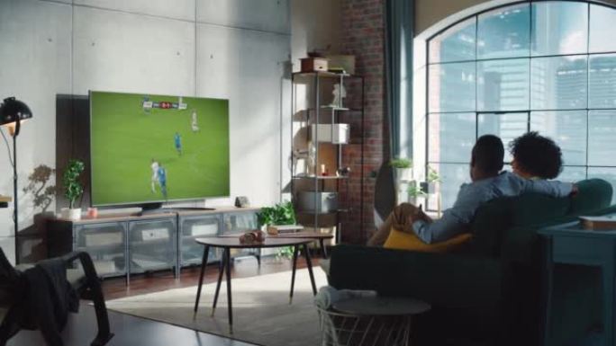 黑人足球迷夫妇晚上在沙发上放松，在公寓里观看冠军决赛。兴奋的伙伴，男女朋友为最喜欢的足球队欢呼。杯赛