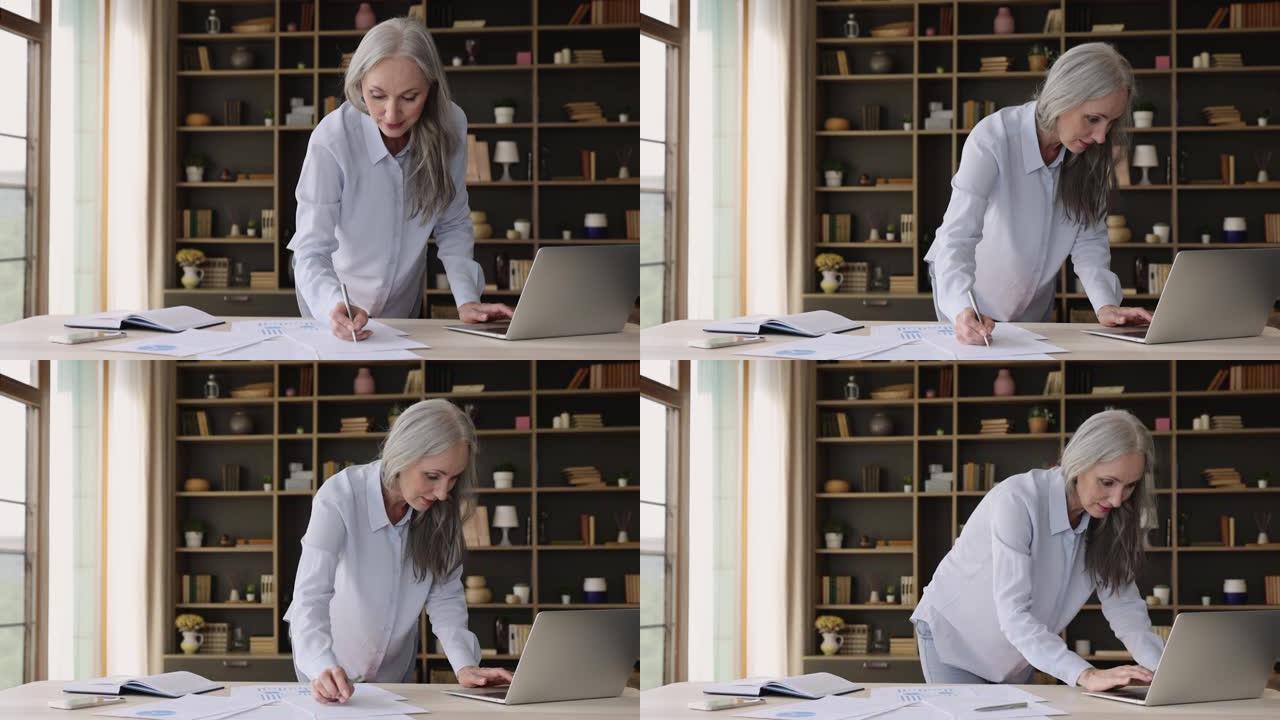 年长的女商人忙于制作演示文稿，使用笔记本电脑，做文书工作