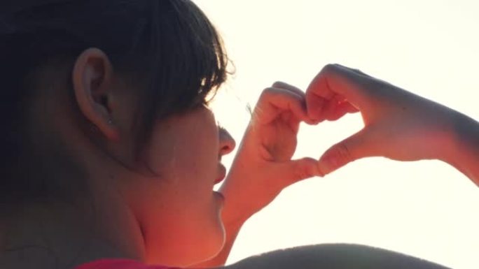 4k视频片段，一名年轻女子在外面用手指露出心形