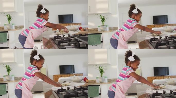 快乐的非洲裔美国女孩在厨房里滚动面团