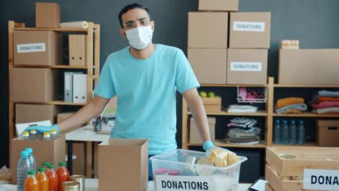 中东志愿者戴着口罩站在慈善公司捐赠食品杂货的桌子旁