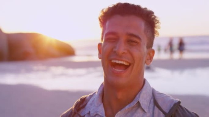 4k视频片段，一个英俊的年轻人独自站在沙滩上，在日落时大笑