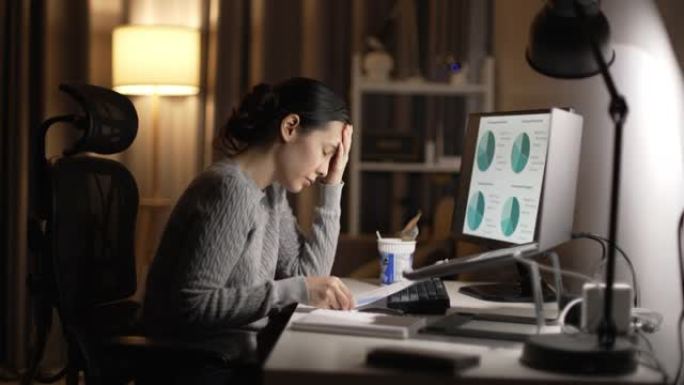 特写疲倦的女人工作到很晚与笔记本电脑在家里