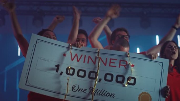 多样化游戏玩家电子竞技团队视频游戏锦标赛的获胜者庆祝胜利欢呼和举起1,000,000美元奖金演示支票