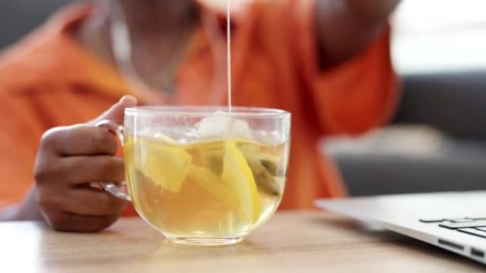 柠檬茶，热饮料和自由职业者坐在家里时将茶袋浸入杯子中以保持健康。喝，放松和女性的手，以排毒健康饮食或