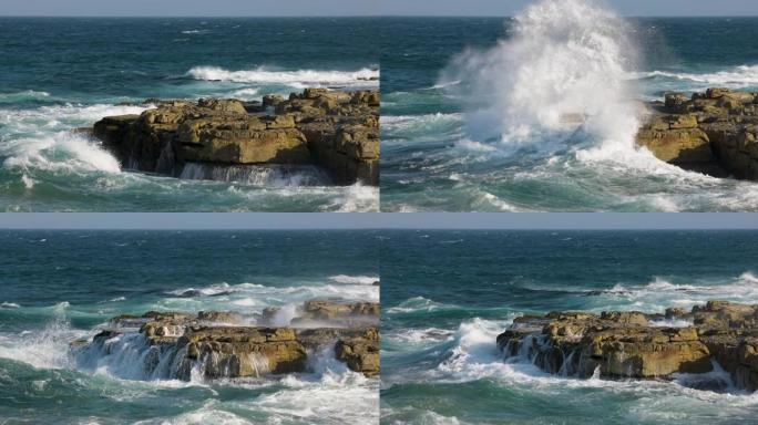 在岩石海岸线上冲破岩石的波浪的空中慢动作视图