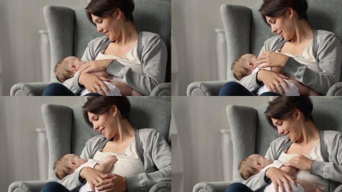 年轻女子坐在舒适的扶手椅上母乳喂养她的新生婴儿