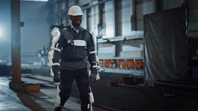 黑人非裔美国工程师正在测试一种未来派仿生外骨骼，并自豪地将其佩戴在一家重型钢铁工业工厂中。成功的承包