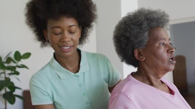 快乐的非洲裔美国女理疗师帮助高级女病人在家锻炼