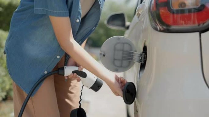 亚洲女人正在打开汽车引擎盖为他的电动汽车加油。