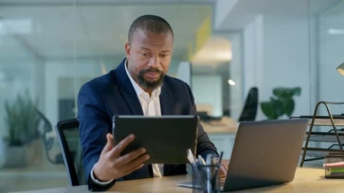办公室里的黑人，晚上在办公桌上处理平板电脑和笔记本电脑的分析工作。非洲商人加班，比较业务数据和数字，