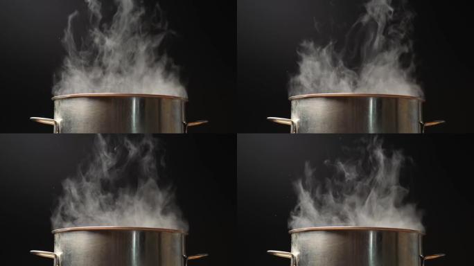 厨房里的锅和蒸汽。烹饪时蒸汽从锅里出来。黑色背景上的平底锅开水。慢动作镜头