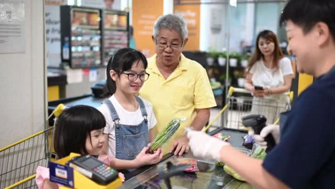 一名亚洲华裔高级男子在周末与孙女一起退房并购买杂货