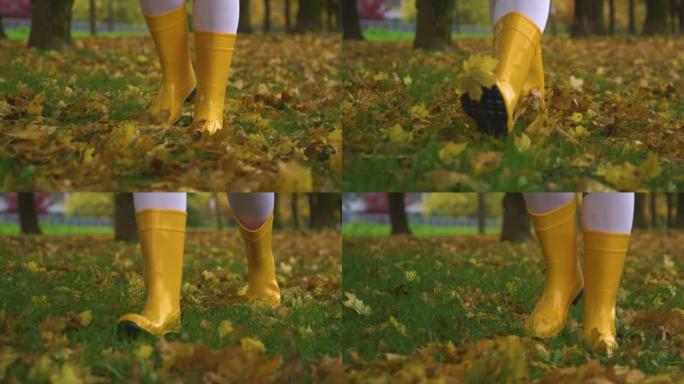 低角度: 穿着瑜伽裤和橡胶靴的女人沿着树叶覆盖的小径行走
