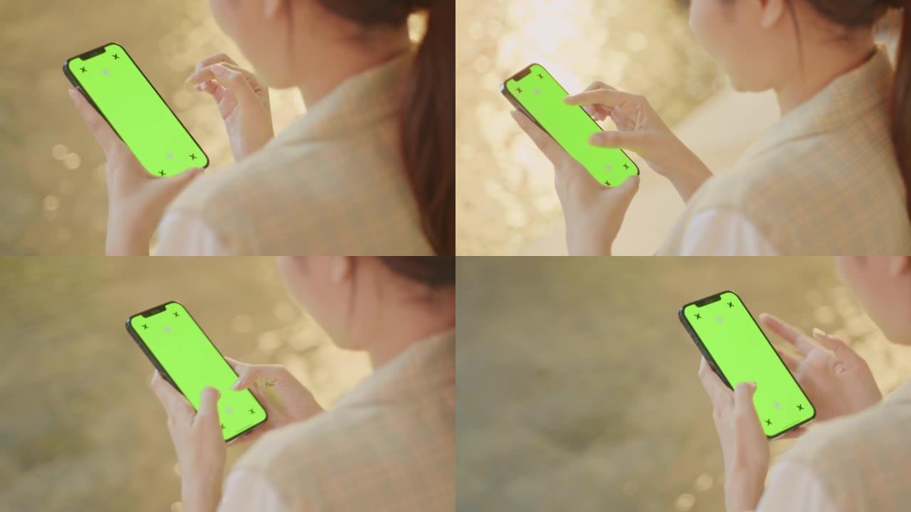特写女人手在夜间使用带色度键绿屏的智能手机