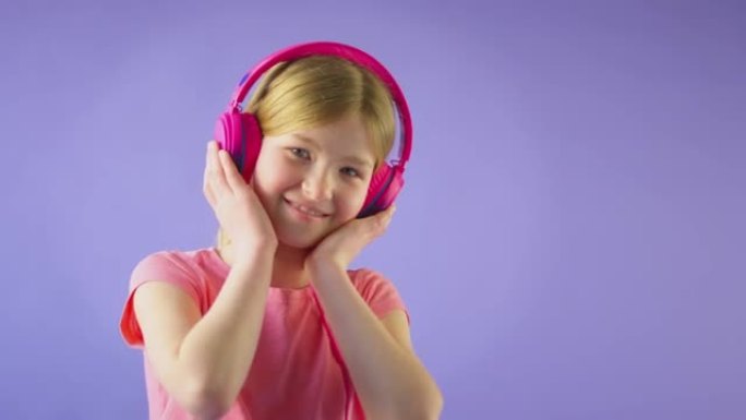 戴着无线耳机的女孩在黄色演播室背景下听音乐的演播室镜头 -- 慢动作镜头