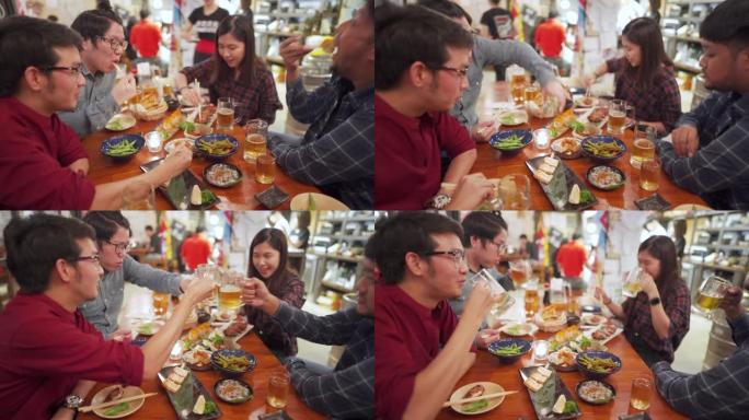 一群亚洲工薪人员在日本居酒屋用餐和欢呼食物和啤酒