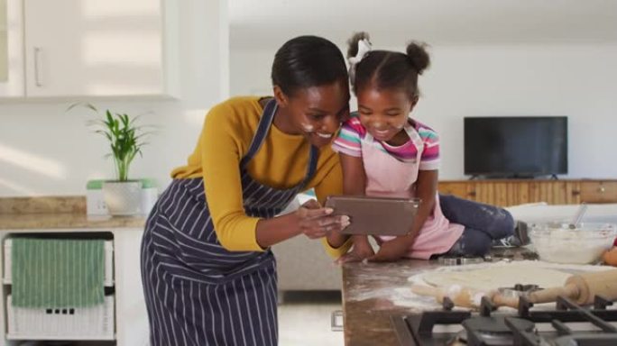 快乐的非洲裔美国母女在厨房做饭看数字平板电脑