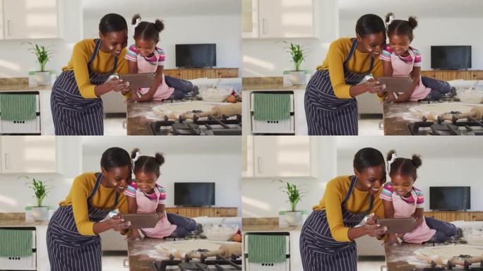 快乐的非洲裔美国母女在厨房做饭看数字平板电脑