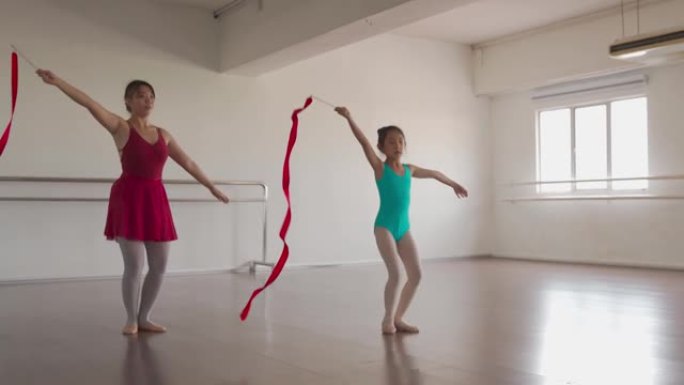 亚洲中国少女在体操学校和小学生一起用彩带练习艺术体操。芭蕾舞学校。