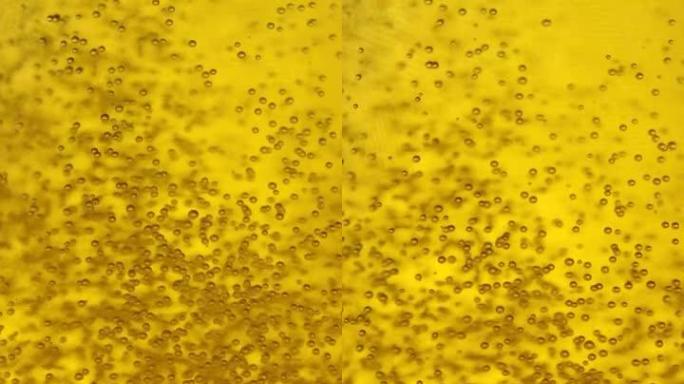 垂直: 微小的二氧化碳气泡漂浮在金色啤酒周围，倒入玻璃杯中。
